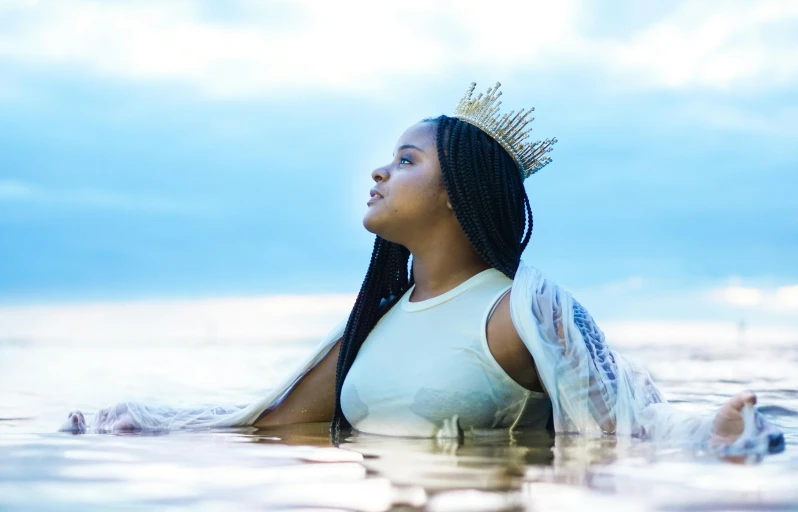 a woman wearing a crown and laying down in water