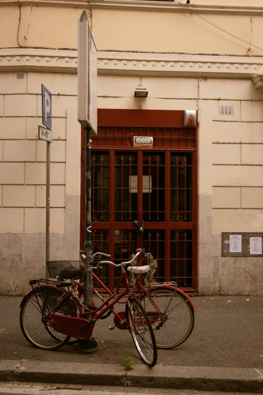 two red bicycles are locked against a red sign