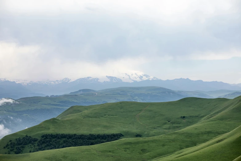 mountains and valleys are seen with green grass on either side