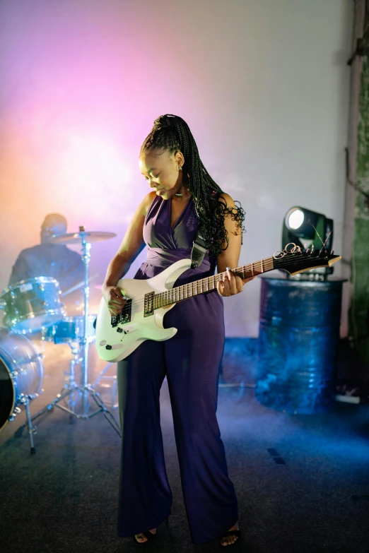 a woman playing a white guitar in a music studio