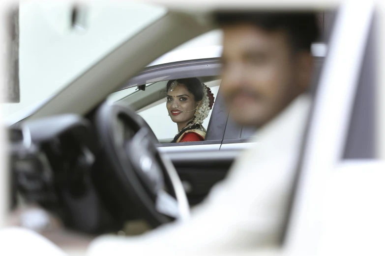 the man and woman are in the car looking at the mirror