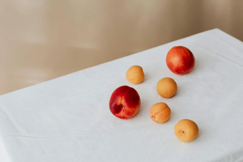 a group of small peachs sit on a white table cloth