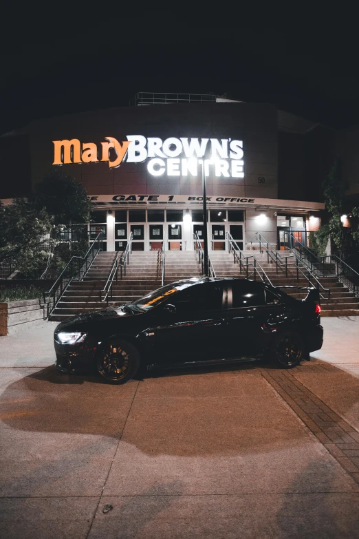 a black car sitting outside of a restaurant at night