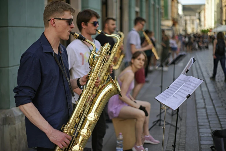 people in a row with instruments sitting on the side walk