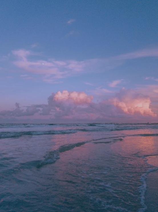 the waves are hitting on the shore and a beautiful sky in the background