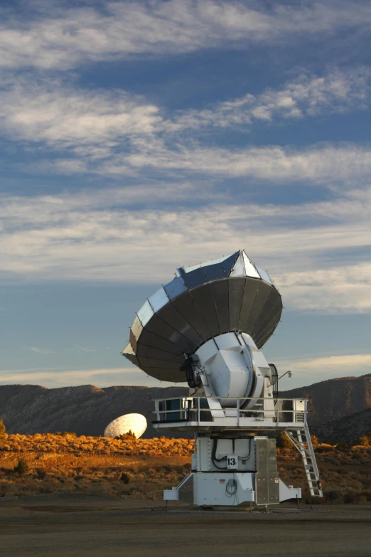 a very large white satellite dish in the middle of an open field