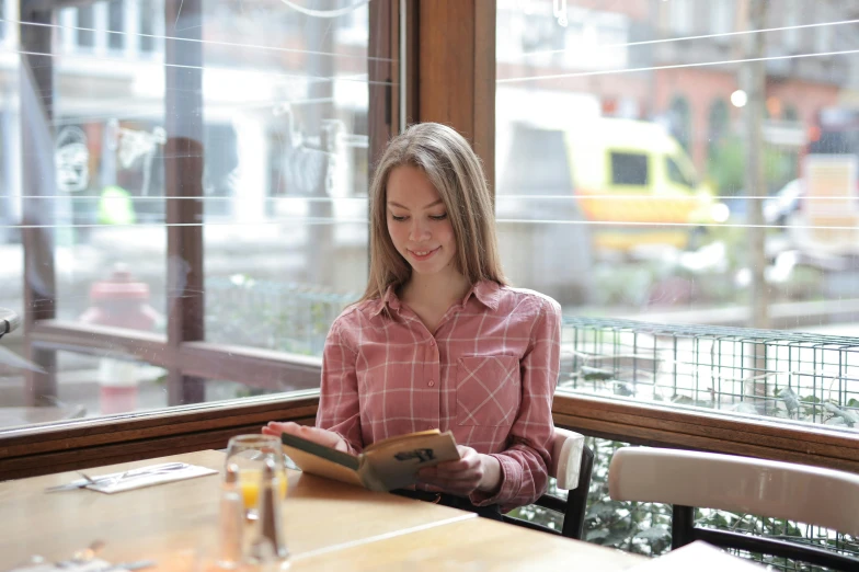 a woman is sitting at the table reading