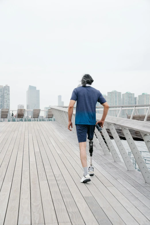 a man walking across a bridge near a city