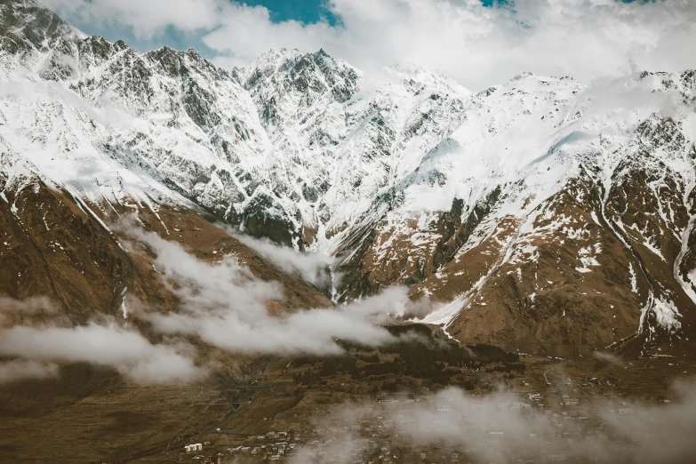 some clouds floating out on the ground in front of a mountain