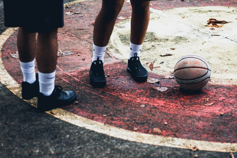 a basketball ball in the street with two men with socks on standing by it