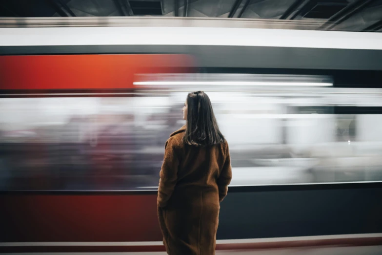 a woman stands in front of a train as it passes