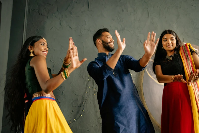 a group of people standing in front of a wall clapping