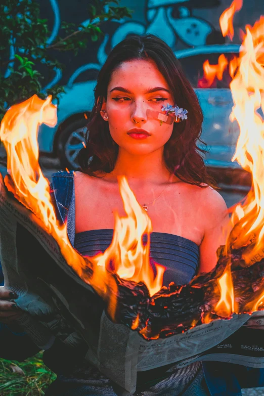 girl sitting on the ground in front of flames with her hands on her hip