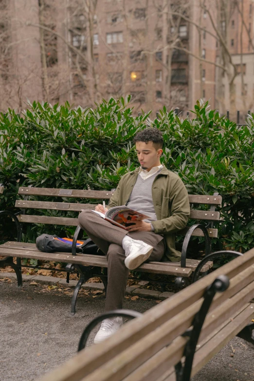 the young man is sitting on the wooden bench