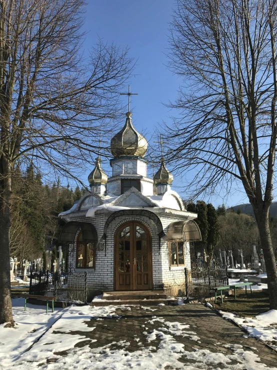 the small chapel with its front door is surrounded by snowy trees