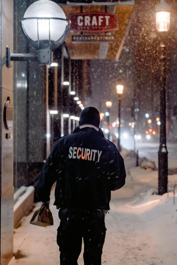 a security man walking down the sidewalk during a snow storm