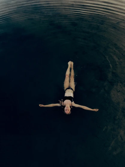a girl swimming alone in a lake with her bikini on