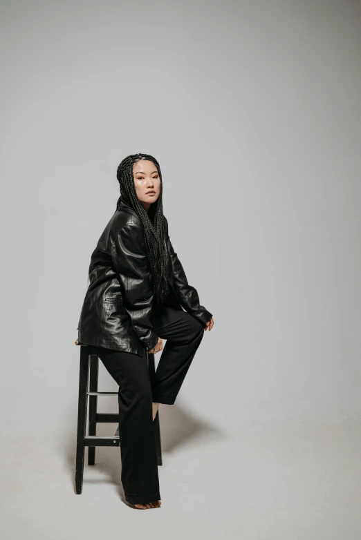 a person wearing black clothes sitting on a stool