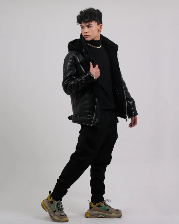 a young man with a leather jacket, black pants, and sneakers