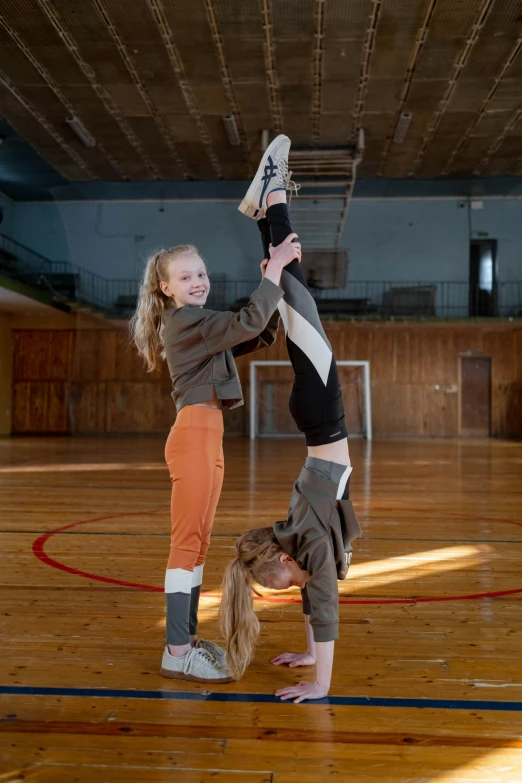 two young ladies doing different exercises on a wooden court