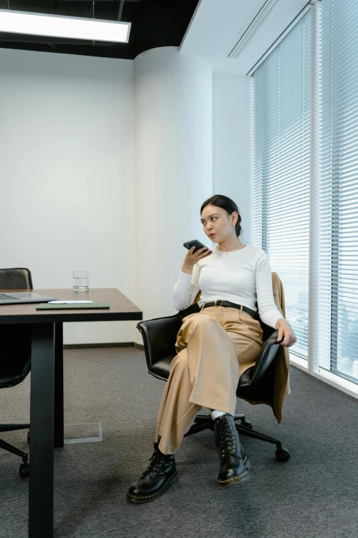 a woman sitting at a conference table talking on a cellphone