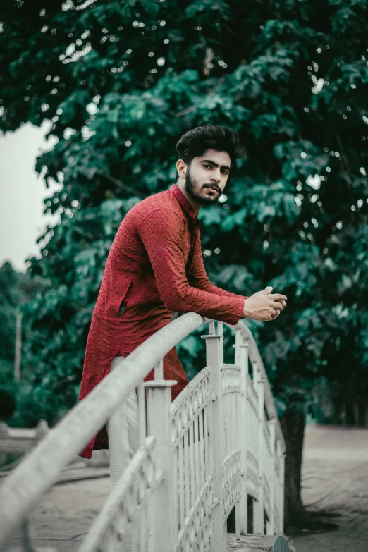 a man wearing a red jacket and standing on a bridge