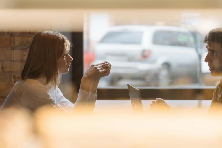 a man and a woman sit and talk on a restaurant table