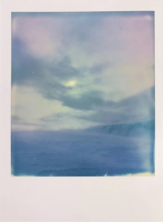 an image of cloudy sky over water and mountains