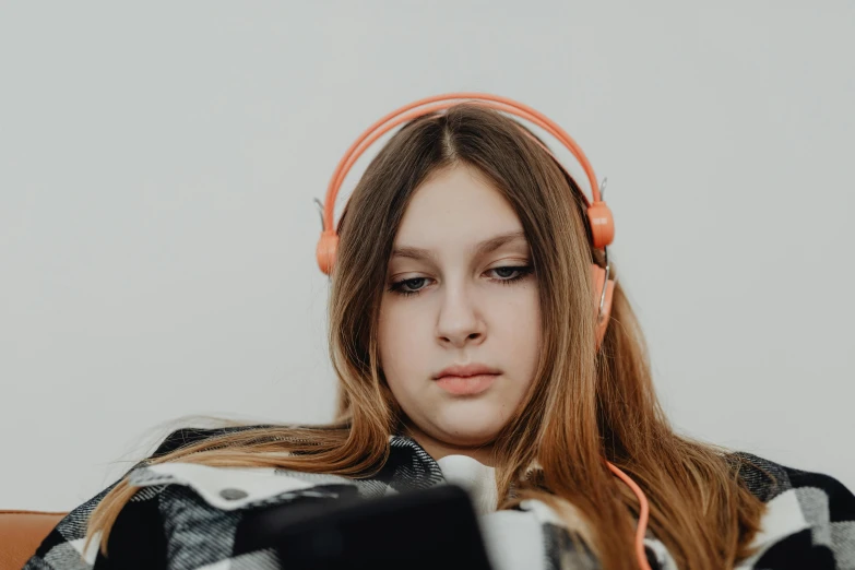 a beautiful young woman wearing headphones and looking at a laptop