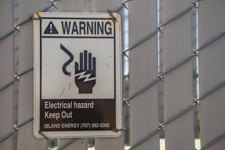 a sign posted on a fence stating that there is electrical hazard keep out