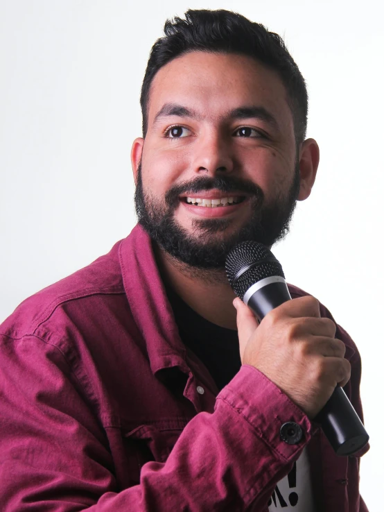 a man in a maroon shirt is holding a microphone