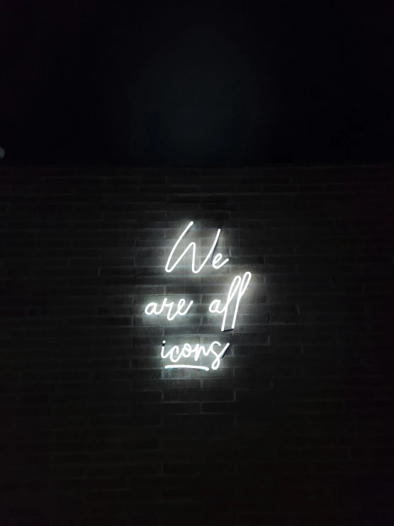 we are all going neon sign against dark wall