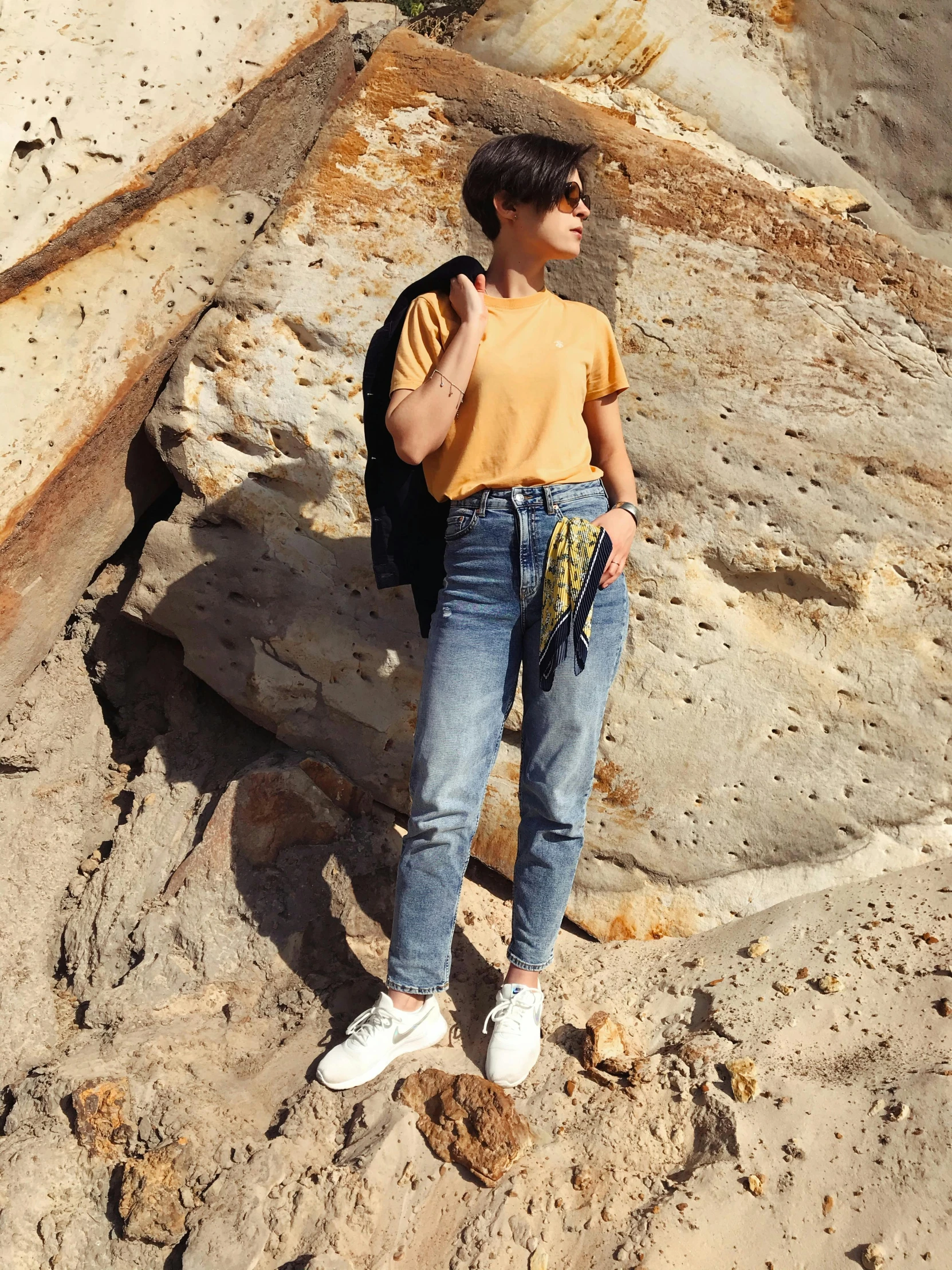 a woman in a yellow shirt is standing on the beach