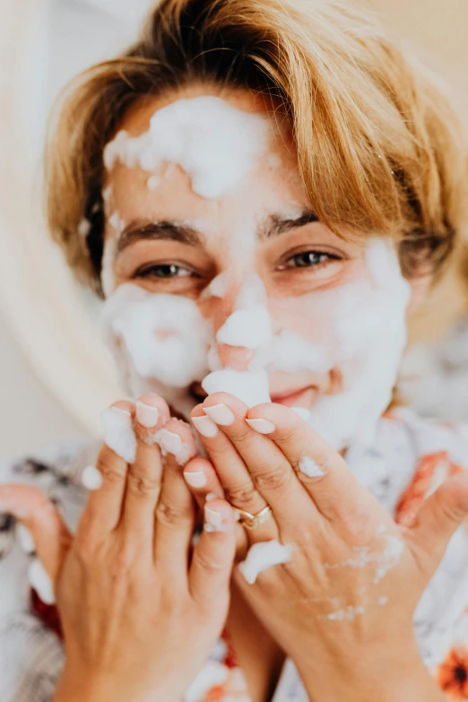 a woman putting a lot of white powder on her face