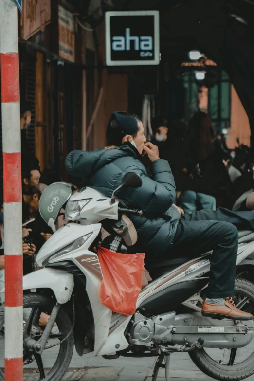 a man sitting on a motor bike talking on his cell phone