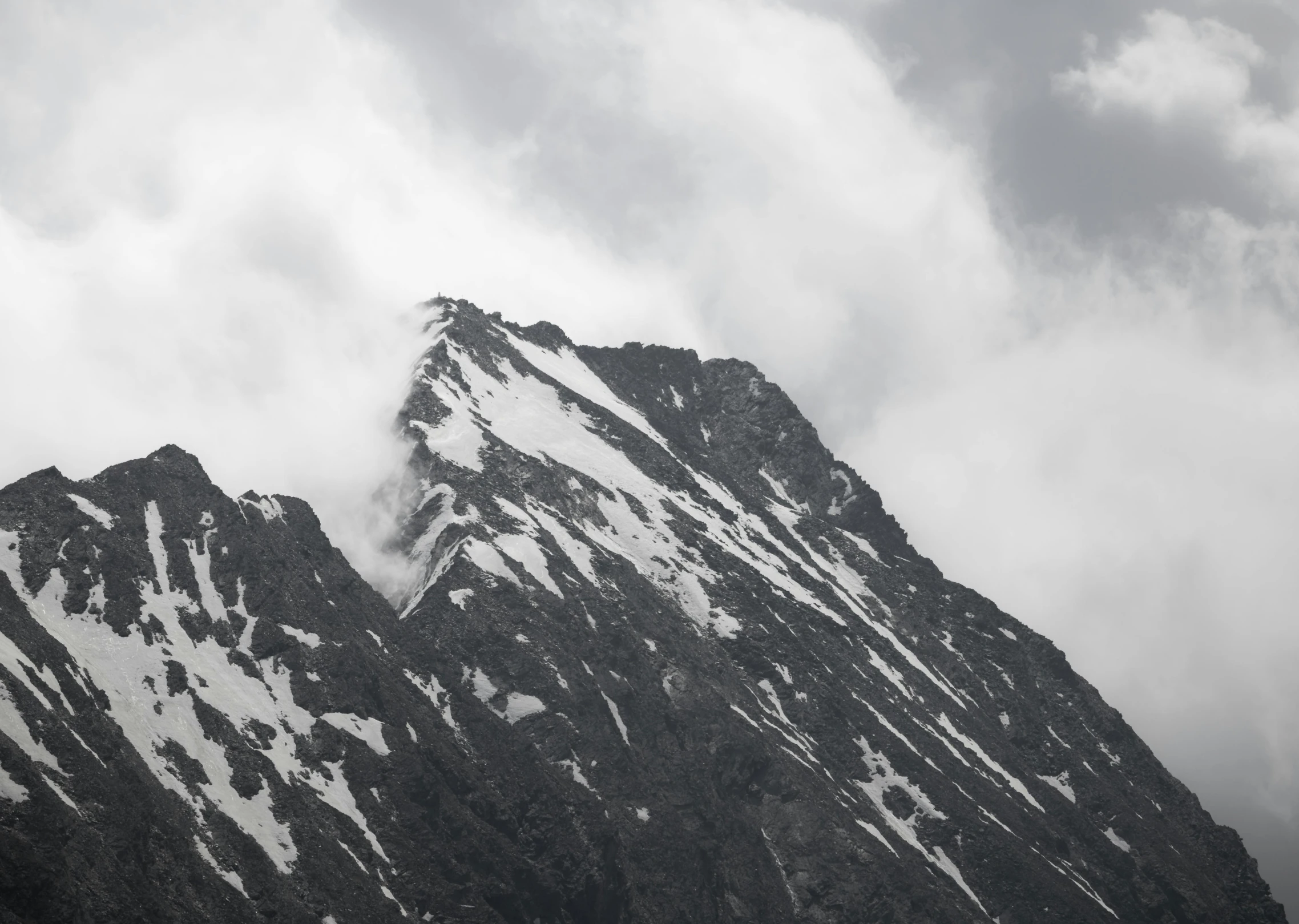 a very tall snowy mountain with some clouds in the background