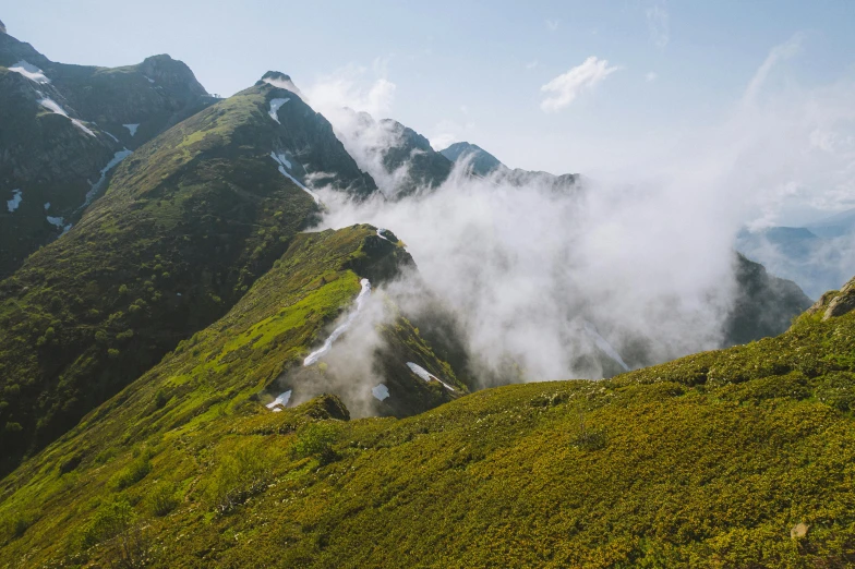 a lush green valley covered in snow and clouds