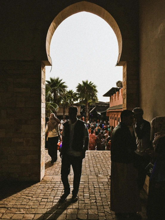 people walk in an arched walkway near other people