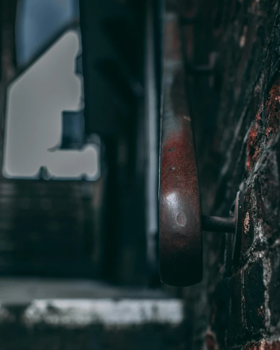 a door handle hangs from an old brick wall