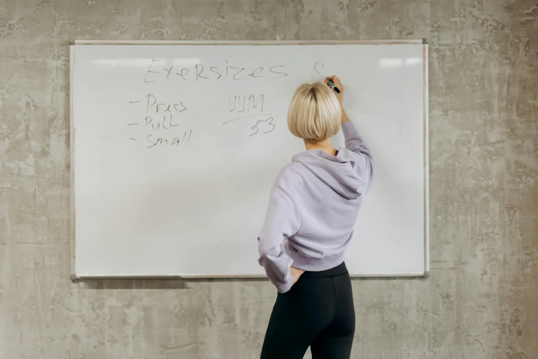 the woman is standing in front of a large whiteboard