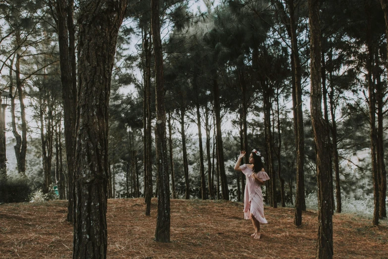 a woman is standing in the middle of a forest