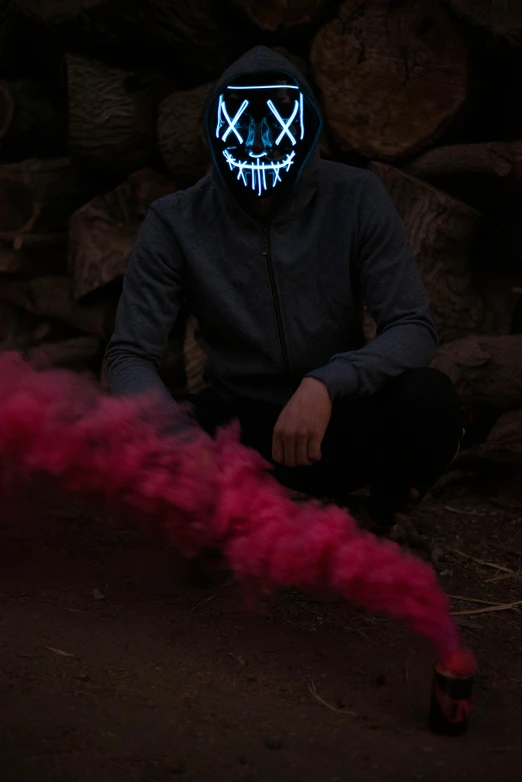 a man sitting on a floor wearing a red smoke bomb and blue light glowing mask