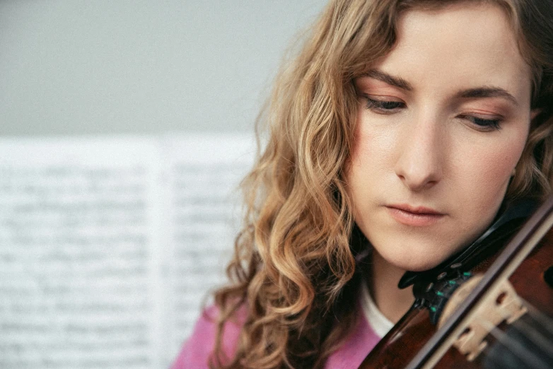 a young woman is playing violin while wearing long hair