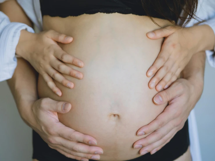 a pregnant woman holds her stomach as she holds the 