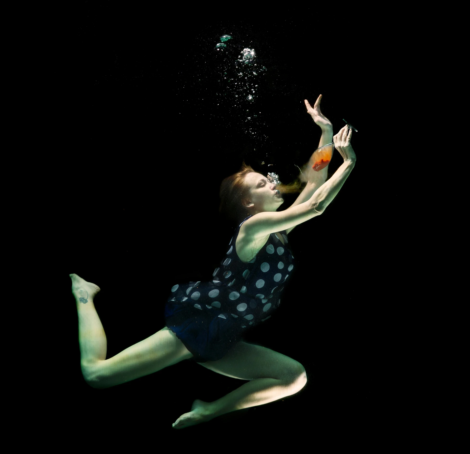 a woman underwater in the dark reaching for soing