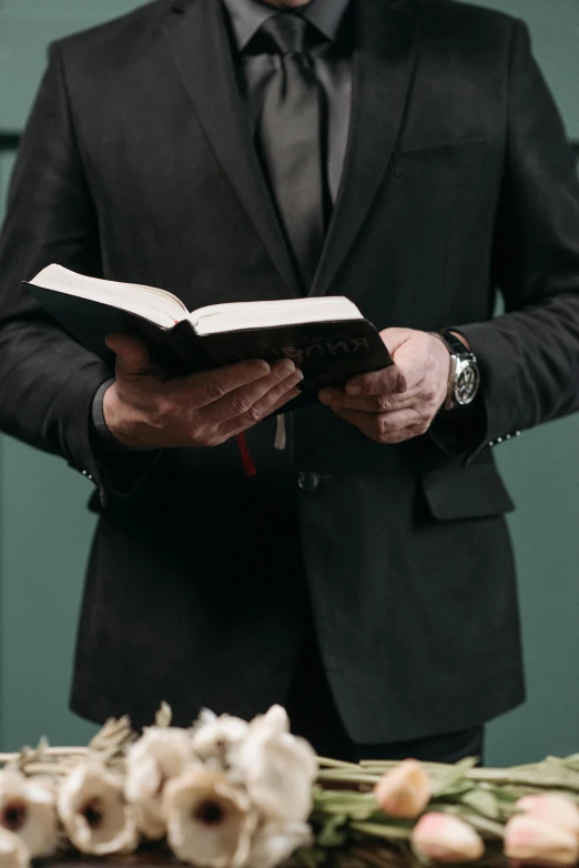 a man in a black suit holding an open book