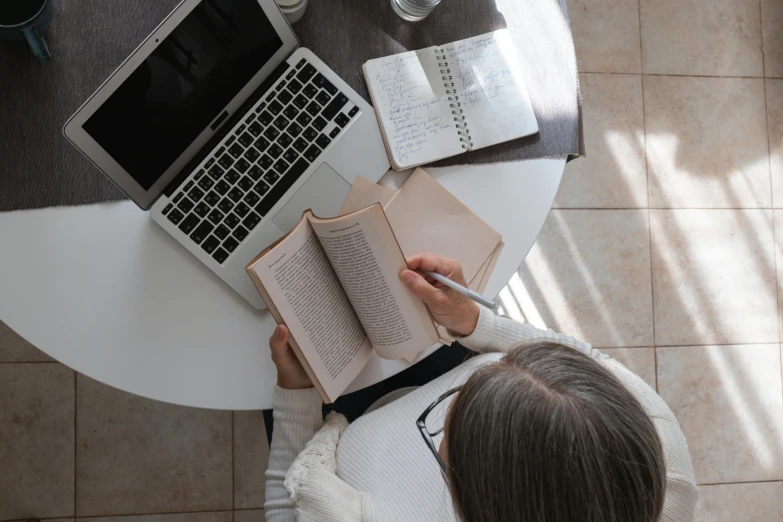 a woman sitting at a table working on an open book