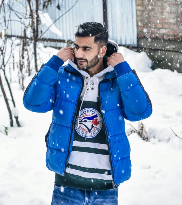 a man in the snow on the phone and wearing a jacket