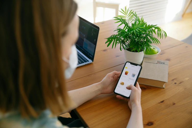 a girl sitting at a table using a smart phone