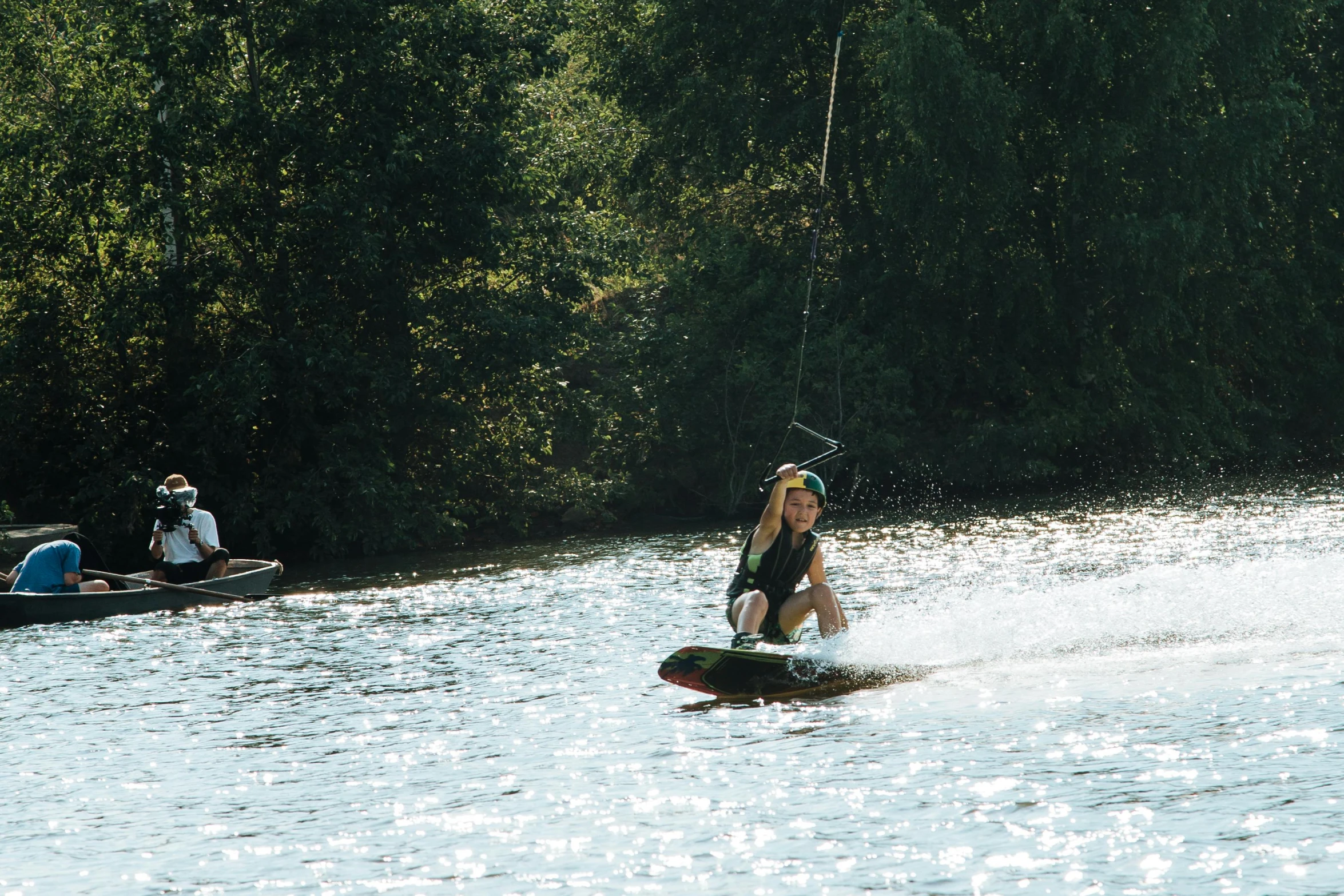 a woman in black wetsuit wakeboarding on lake